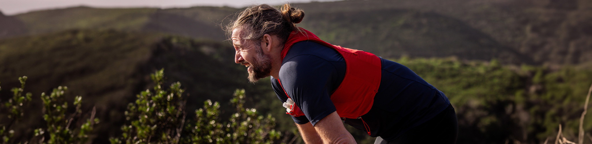 Shop trail new season. Man resting after a run on a side of a hill