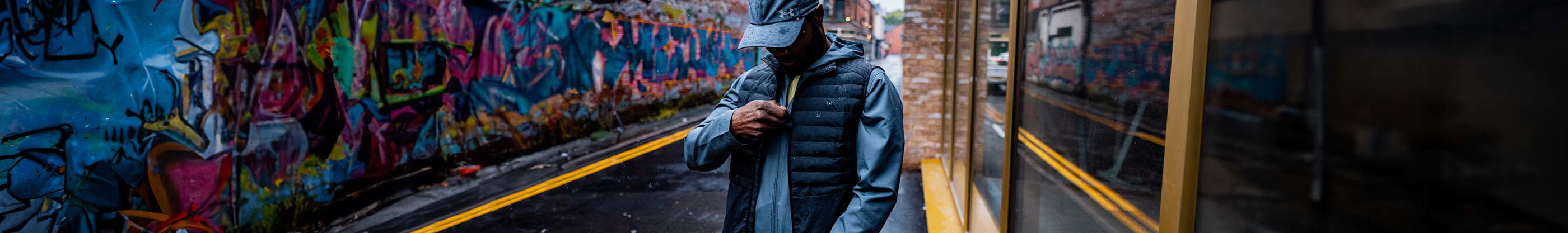 Shop new season running jackets and gilets. Man putting on jacket.